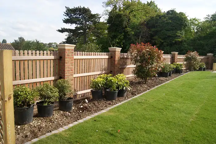 Decorative garden fencing in Gloucester with wooden panels and brick pillars surrounded by greenery.